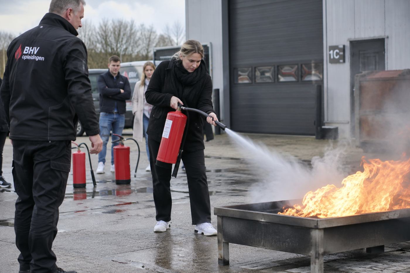 Cursist blust een vuur onder begeleiding van een instructeur
